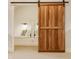 The light filled bedroom is viewed through an open wooden sliding barn door at 7613 W Stonegate Dr, Zionsville, IN 46077