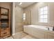 A modern bathroom includes a glass shower and a soaking tub, with natural light enhancing the space's inviting ambiance at 7613 W Stonegate Dr, Zionsville, IN 46077