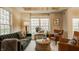 Cozy living room showcasing a plush green sofa, leather chairs, and ample natural light at 7613 W Stonegate Dr, Zionsville, IN 46077