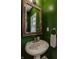 Chic powder room with green walls, a rustic mirror, and a pedestal sink at 7613 W Stonegate Dr, Zionsville, IN 46077