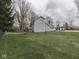 Wide shot of back exterior and large, grassy, fenced yard with mature trees and fire pit at 8160 Bold Forbes Ct, Indianapolis, IN 46217