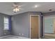 Bedroom featuring a ceiling fan, gray walls, a window with curtains, and a door to the hallway at 8160 Bold Forbes Ct, Indianapolis, IN 46217