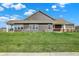 Backyard view with a lush green lawn, back of the house, and covered porch on a sunny day at 8570 Hudson Way, Brownsburg, IN 46112