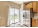 Bright kitchen features stainless steel refrigerator, wood cabinets, and a sliding glass door to the backyard at 9763 Rolling Plain Dr, Noblesville, IN 46060