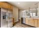 Updated kitchen with stainless steel refrigerator, wood cabinets, and a view into the open living space at 9763 Rolling Plain Dr, Noblesville, IN 46060