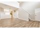 Open-concept living space with wood laminate flooring, staircase, and a view into the adjacent kitchen at 9763 Rolling Plain Dr, Noblesville, IN 46060
