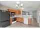 Compact kitchen with wood cabinets, black appliances, and a view into the living area at 10861 Tealpoint Dr, Indianapolis, IN 46229