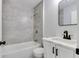 Modern bathroom with gray tiled walls, a bathtub, a new toilet, and a stylish vanity with a black faucet at 1125 N Colorado Ave, Indianapolis, IN 46201