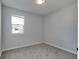 A simple bedroom with soft carpet, white walls, and a bright window offering ample light and outdoor views at 1125 N Colorado Ave, Indianapolis, IN 46201