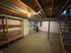 Unfinished basement featuring exposed ceiling, concrete flooring, utility appliances, and wooden shelving unit at 1235 Cottonwood Ct, Carmel, IN 46033