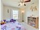 Inviting bedroom featuring a ceiling fan, window view, and a bookshelf filled with colorful books at 12723 Pinetop Way, Noblesville, IN 46060