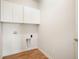 Bright laundry room with wood-look floors, white cabinets, and convenient utility connections at 12914 Shiraz Ln, Fishers, IN 46037