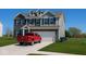 Beautiful two-story home with gray siding, brick accents, blue shutters, well-manicured lawn, and a red pickup in the driveway at 1573 Vera Blvd, Danville, IN 46122