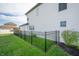 Side view of a backyard with a black metal fence, lush green grass, and a two-story home at 1614 Waterleaf Dr, Westfield, IN 46074