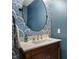 Half bathroom features designer wallpaper and a wood vanity with a white countertop and oval mirror at 1614 Waterleaf Dr, Westfield, IN 46074