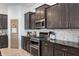 This kitchen features dark cabinets, granite countertops, stainless steel appliances, and mosaic tile backsplash at 1614 Waterleaf Dr, Westfield, IN 46074