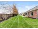 Large backyard with lush green grass, mature trees, manicured garden beds and a beautiful brick house at 16350 Quartz Dr, Noblesville, IN 46060