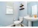 Elegant powder room featuring a pedestal sink, modern fixtures, and stylish decorative shelves at 17301 Tribute Row, Noblesville, IN 46060