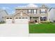 Charming two-story home featuring a well-manicured lawn, a three-car garage, and a welcoming front porch at 17301 Tribute Row, Noblesville, IN 46060