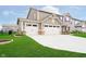 Expansive driveway leading to a three-car garage, surrounded by lush green lawn and tidy landscaping at 17301 Tribute Row, Noblesville, IN 46060