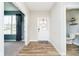 Inviting foyer with wood-look flooring, leading to a naturally lit living space and adjacent powder room at 17301 Tribute Row, Noblesville, IN 46060