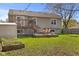 Back exterior view of home, featuring a large backyard, deck, and mature trees at 1736 Sandoval Ct, Indianapolis, IN 46214