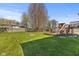 A large backyard with mature trees, a fire pit, a grill, and deck with seating at 1736 Sandoval Ct, Indianapolis, IN 46214