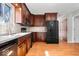 Well-lit kitchen featuring dark wood cabinets, modern black appliances, and a durable wood floor at 315 Heritage Ct, Fishers, IN 46038