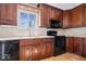 Close-up of a well-lit kitchen featuring dark wood cabinets and modern black appliances at 315 Heritage Ct, Fishers, IN 46038