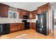 Well-lit kitchen featuring dark wood cabinets, modern black appliances, and a durable wood floor at 315 Heritage Ct, Fishers, IN 46038