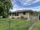 Property with chain link fence, stone exterior, and manicured lawn at 3315 Hillcrest Dr, Columbus, IN 47203