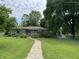 Charming single-story home featuring a lush lawn, mature trees, and a welcoming walkway at 3315 Hillcrest Dr, Columbus, IN 47203