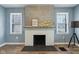 Close up on living room fireplace with whitewashed brick, decorative mantel, and lots of light from the windows at 3433 Brouse Ave, Indianapolis, IN 46218
