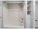 Shower with white tub surround and tiled walls, with storage shelves at 3703 Dubarry Rd, Indianapolis, IN 46226