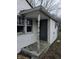 Weathered front entrance with a green door, white siding, and a damaged window at 4210 E Naomi St, Indianapolis, IN 46203