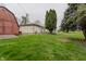 Backyard of a ranch-style house with a wood deck, an expansive, well-manicured yard, and a red shed at 5510 Chelsea Rd, Indianapolis, IN 46241