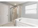 A modern bathroom featuring a glass door shower, soaking tub, and bright window at 559 Hythe Way, Westfield, IN 46074