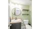 Cozy half-bath with a pedestal sink, floating shelves and a modern round mirror at 5820 Marble Ct, Anderson, IN 46013