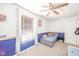 A bright bedroom featuring blue accent wall, ceiling fan, and a sunny window at 5820 Marble Ct, Anderson, IN 46013