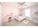 A bright bedroom featuring pink walls, ceiling fan, and a sunny window at 5820 Marble Ct, Anderson, IN 46013