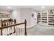 Upstairs hallway featuring hardwood railing and access to custom built-in bookshelves at 5861 Dawnwood Dr, Carmel, IN 46033