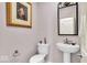 Cozy powder room with pedestal sink, toilet, and ornate framed mirror at 5861 Dawnwood Dr, Carmel, IN 46033