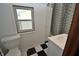 Bathroom features a window, storage cabinet, shower/tub with polka dot shower curtain, checkerboard flooring, and sink at 609 E Columbus St, Martinsville, IN 46151