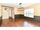Inviting dining area with modern chandelier, wainscoting, wood floors, and access to stairway at 6479 Enclave Blvd, Greenwood, IN 46143