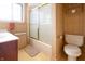Bathroom with neutral wallpaper, shower with glass sliding door, vanity, toilet, and window at 720 22Nd St, Columbus, IN 47201
