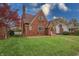 View of a brick home featuring a gabled roof, arched entry, and lush, green landscaping at 720 22Nd St, Columbus, IN 47201