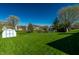 Expansive backyard featuring lush green grass, mature trees, a shed, and pond at 7230 Carrie Dr, Indianapolis, IN 46237