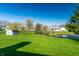 Expansive backyard featuring lush green grass, mature trees, a shed, and pond at 7230 Carrie Dr, Indianapolis, IN 46237