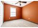 Empty bedroom featuring a ceiling fan, a window, neutral carpet, and burnt orange walls at 7230 Carrie Dr, Indianapolis, IN 46237