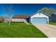 Charming single-story home featuring a well-manicured lawn, a blue garage door, and a brick facade at 7230 Carrie Dr, Indianapolis, IN 46237